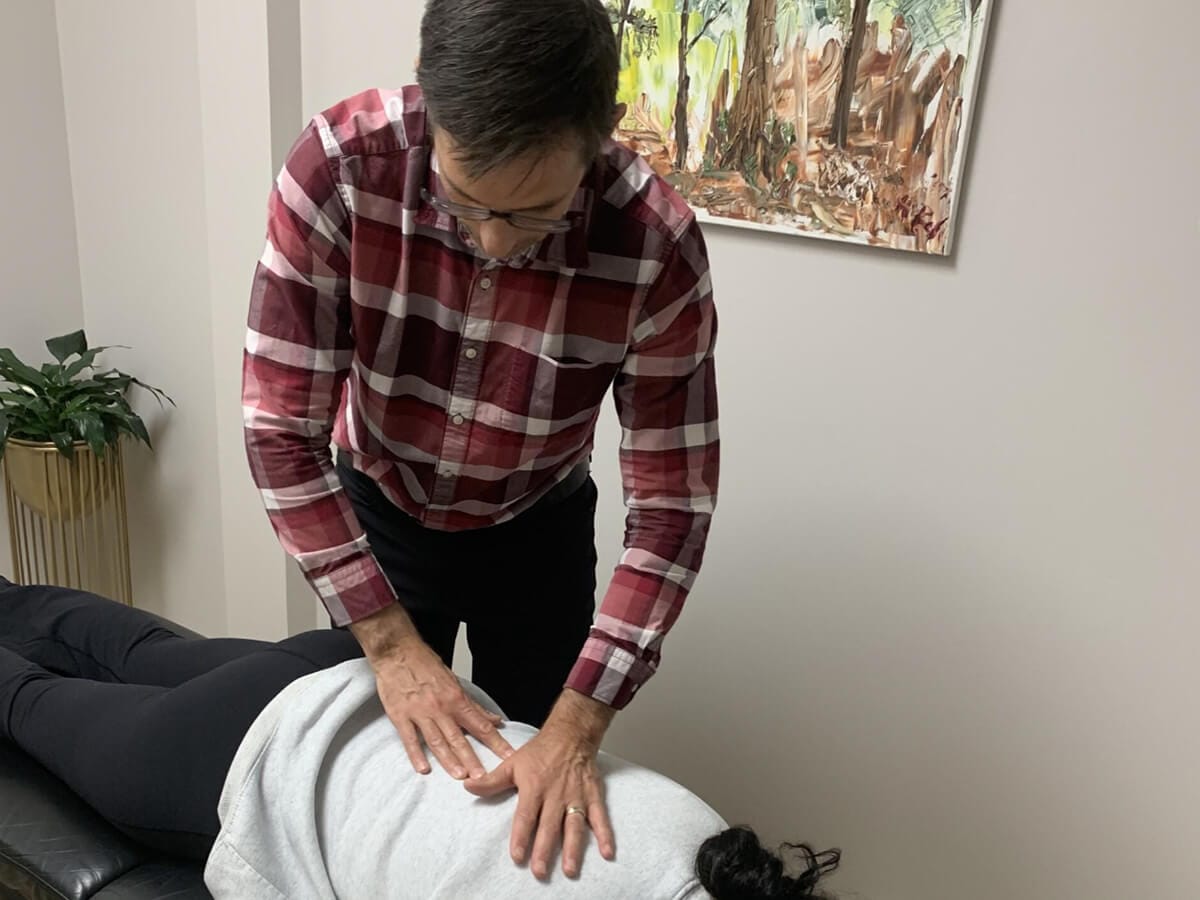 Chiropractor assessing spinal alignment of a patient