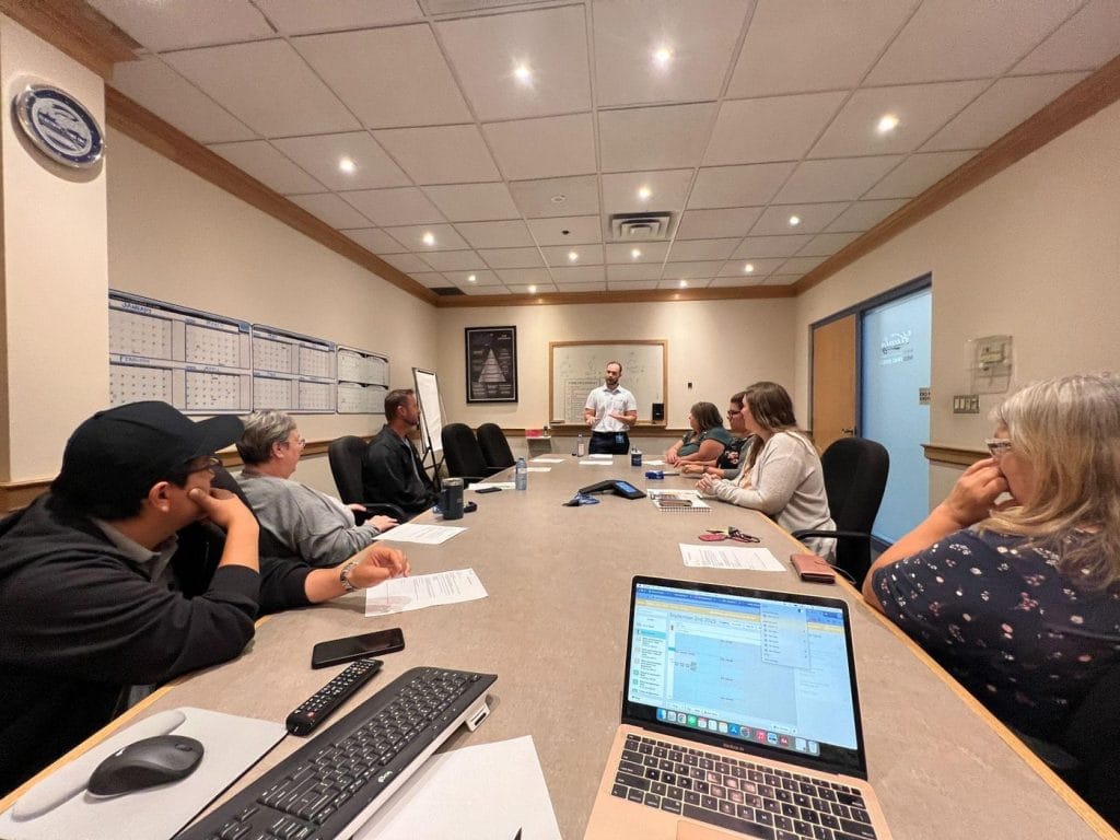 Dr. Adrian Bugiel giving a spinal health talk to employees around a boardroom table