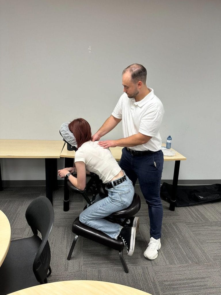 Dr. Adrian Bugiel giving a seated chair massage to an employee at a workplace massage day
