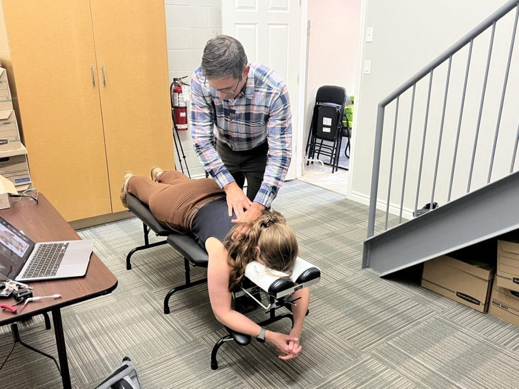 Dr. Nik Dukovac performing a five minute spinal screening on an employee at a portable table